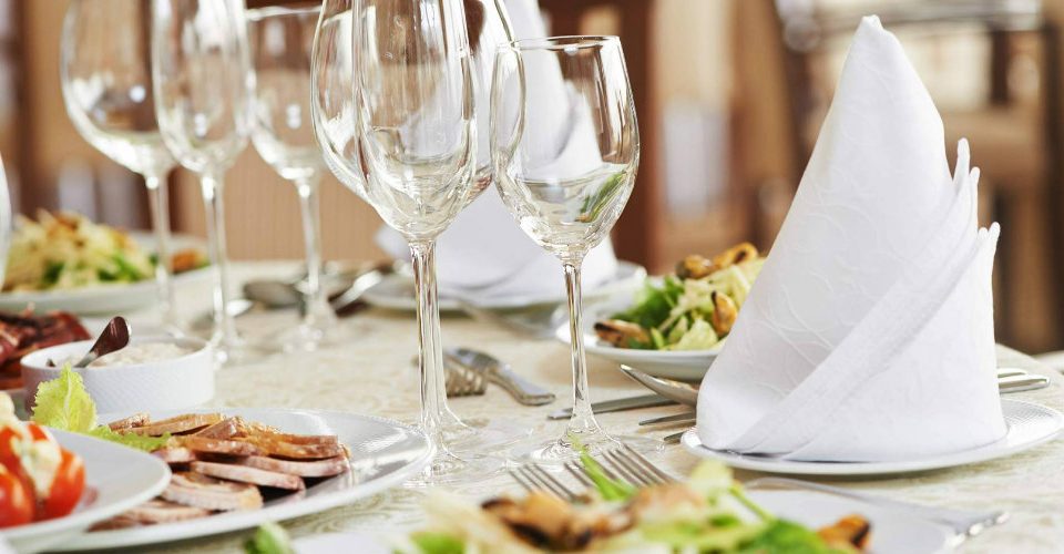 A neatly arranged table featuring white plates and polished silverware, ready for a dining experience.